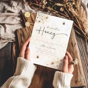 May include: A bridal shower invitation with a watercolor background of flowers and honeycombs. The text reads "She found her Honey" and includes details for the event, including the bride-to-be's name, date, time, and location.