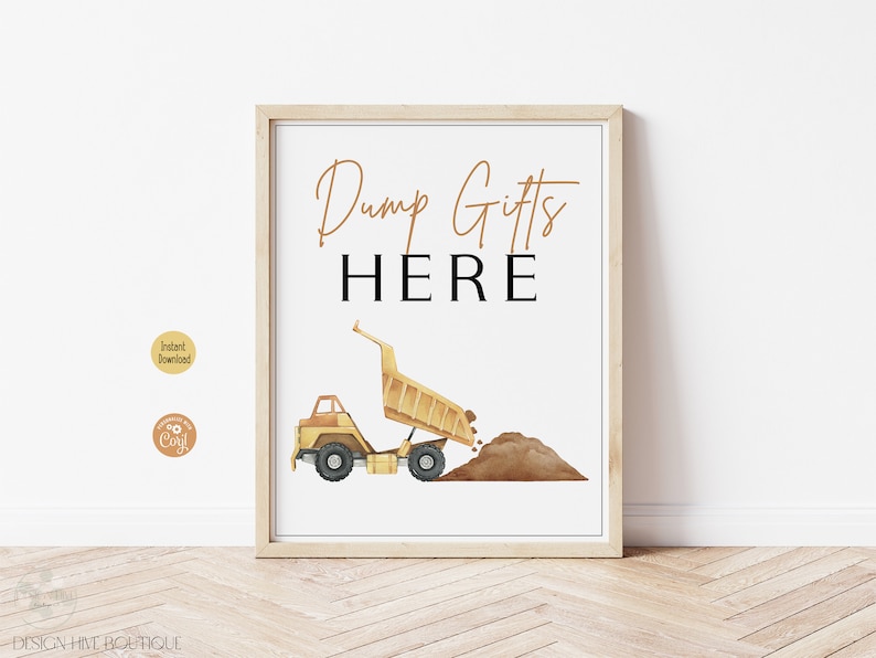 May include: A framed print with the words "Dump Gifts HERE" in gold and black. A yellow watercolor dump truck is dumping brown dirt. The print is in a light wood frame and is on a white background.