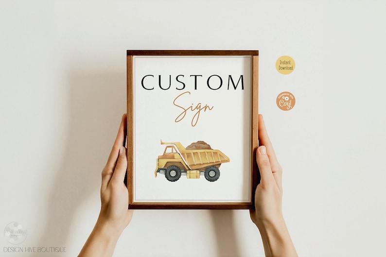 May include: A framed sign with the words "CUSTOM Sign" and a watercolor illustration of a yellow dump truck carrying dirt. The sign has a brown wooden frame and is held by two hands.