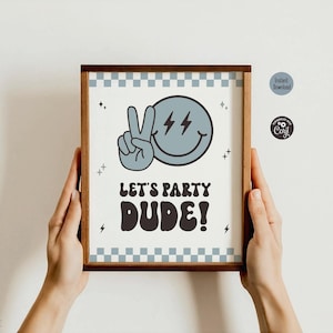 May include: A framed print featuring a light blue smiley face making a peace sign with lightning bolt eyes. The text reads LET'S PARTY DUDE! in a bold, dark font. The border has a light blue and white checkered pattern with small star accents.