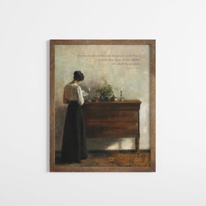 Op de afbeelding: Een ingelijste print van een schilderij dat een vrouw in een wit blouse en een zwarte rok toont die voor een houten dressoir staat. Op het dressoir staan een vaas met bloemen en kaarsen. De print bevat de quote "Gunst is bedrieglijk, en schoonheid is ijdel: maar een vrouw die de HEERE vreest, zij zal geprezen worden." - Spreuken 31:30