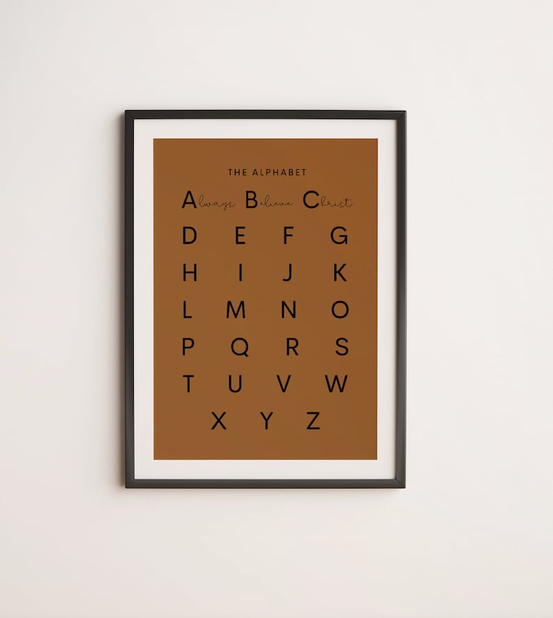 May include: A brown poster with a black frame, featuring the alphabet with the words "Always Believe Christ" written in cursive above the letters.
