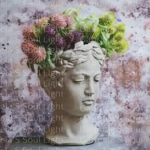 Puede incluir: Un busto de yeso blanco de una mujer con una corona de flores en la cabeza. Las flores son una mezcla de rosa, morado y verde.
