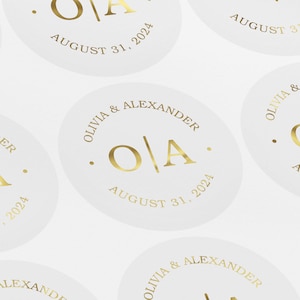 May include: White round stickers with gold lettering. The stickers say "Olivia & Alexander" and "O/A" with the date "August 31, 2024".
