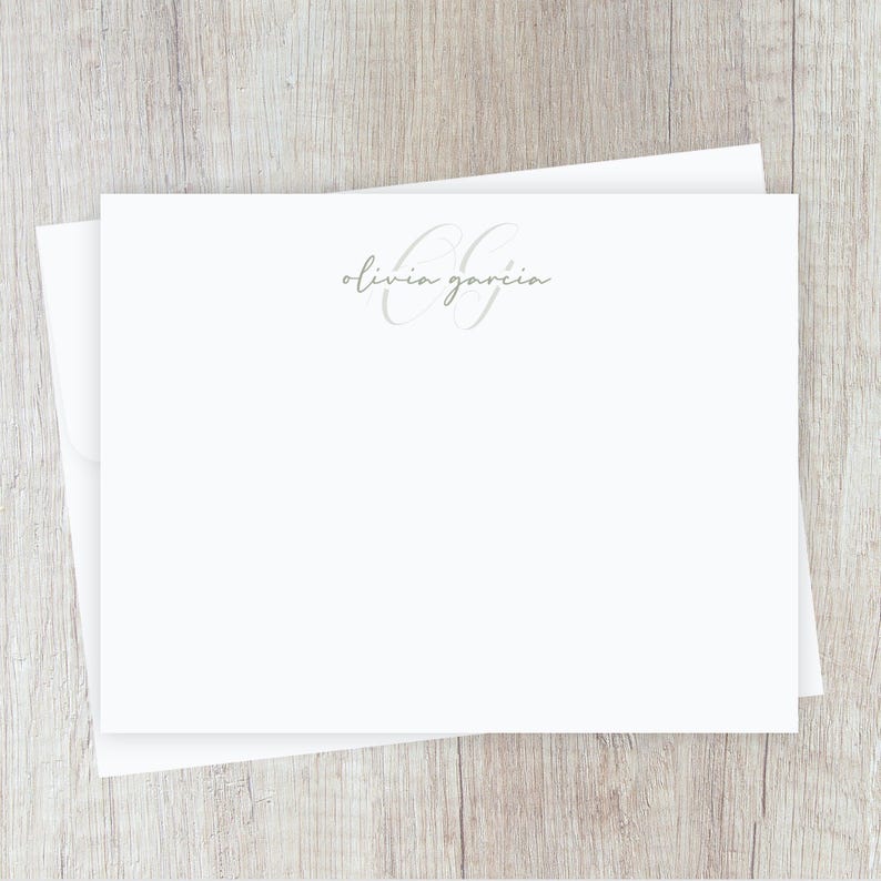 May include: White stationery with a gray script font that says "olivia garcia" and a gray monogram of the letters "OG" in a cursive font.