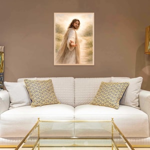 K&ouml;nnte beinhalten: Ein gerahmtes religi&ouml;ses Kunstwerk, das eine Figur in flie&szlig;enden Gew&auml;ndern zeigt, die eine Hand ausstreckt. Das Kunstwerk wird &uuml;ber einem wei&szlig;en Sofa mit gemusterten Kissen ausgestellt. Eine goldene Lampe und ein Glastisch sind ebenfalls zu sehen.