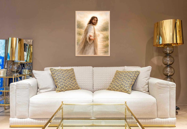 K&ouml;nnte beinhalten: Ein gerahmtes religi&ouml;ses Kunstwerk, das eine Figur in flie&szlig;enden Gew&auml;ndern zeigt, die eine Hand ausstreckt. Das Kunstwerk wird &uuml;ber einem wei&szlig;en Sofa mit gemusterten Kissen ausgestellt. Eine goldene Lampe und ein Glastisch sind ebenfalls zu sehen.