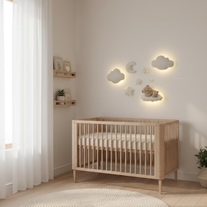 Könnte beinhalten: Ein Kinderzimmer mit einem hellen Holzbettchen und einer Matratze. Wanddekorationen in Form von Wolken, Mond und Sternen sind beleuchtet. Ein runder, beiger Teppich liegt auf dem Boden. Links ist ein Fenster mit transparenten Vorhängen.