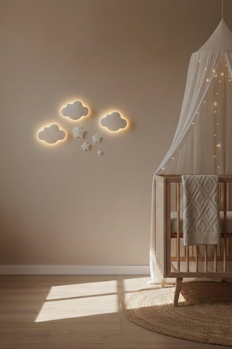 May include: A nursery scene featuring a wooden crib with a canopy and a beige blanket. The wall is adorned with illuminated cloud and star-shaped wall decor. A round woven rug sits on the wooden floor, with sunlight streaming in.