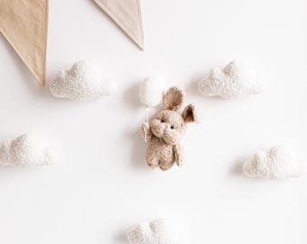 May include: A brown bunny plush toy holding a white balloon, surrounded by white fluffy clouds and a beige and white bunting.