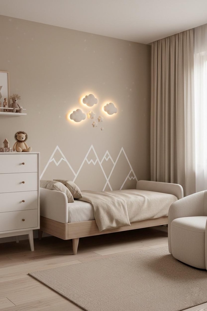May include: A neutral-toned bedroom with a bed, dresser, and armchair. The wall features a mountain mural and cloud-shaped lights. The bed has a beige blanket and pillows. A rug and curtains complete the cozy space.