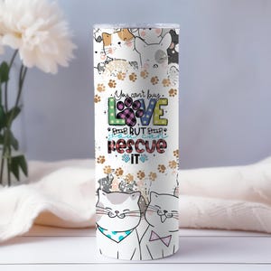 May include: White tumbler with a colorful graphic of cats and dogs. The graphic includes the text "You can't buy love but you can rescue it".