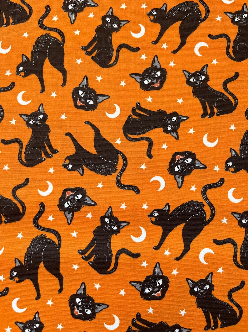 May include: Orange fabric with a repeating pattern of black cats, white stars, and white crescent moons.