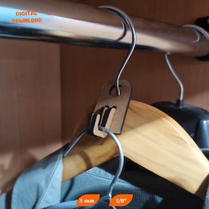 May include: A close-up of a brown cardboard hanger clip with a metal hook. The clip is designed to hang on a standard closet rod and has a small hole in the top for a tag. The clip is 3 mm thick and 1/8 inch wide.