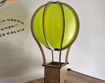 May include: A wooden hot air balloon model with a green balloon and a brown base. The balloon is 3 mm thick and the base is 1/8 inch thick.