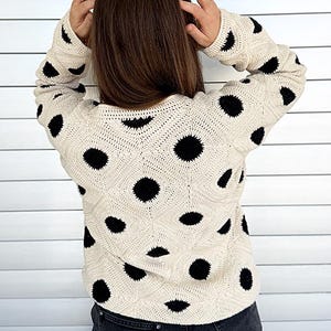 May include: Cream-colored, crocheted sweater with large black polka dots. The sweater has a diamond pattern and long sleeves. The website beautifulcrochetstuff.com is visible at the bottom of the image.