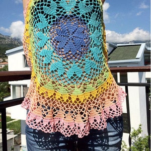 Könnte beinhalten: Ein Regenbogen-Häkeltop mit einem gewellten Saum. Das Top ist aus verschiedenen Farben gefertigt, darunter Pink, Gelb, Grün, Blau und Lila. Das Top ist ärmellos und hat eine lockere Passform.