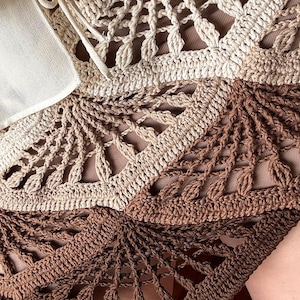 Op de afbeelding: Close-up van een handgemaakt haakwerk in tinten beige en bruin. Het ingewikkelde openwerkontwerp heeft een waaiervormig patroon. De tekst "beautifulcrochetstuff.com" is onderaan zichtbaar.