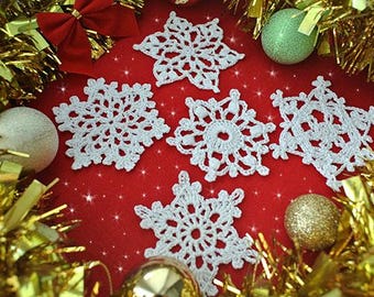 May include: Six white crocheted snowflakes on a red background with gold tinsel and ornaments.