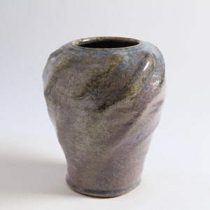 May include: A ceramic vase with a textured, mottled glaze in shades of brown, purple, and green. The vase has a rounded, organic shape.