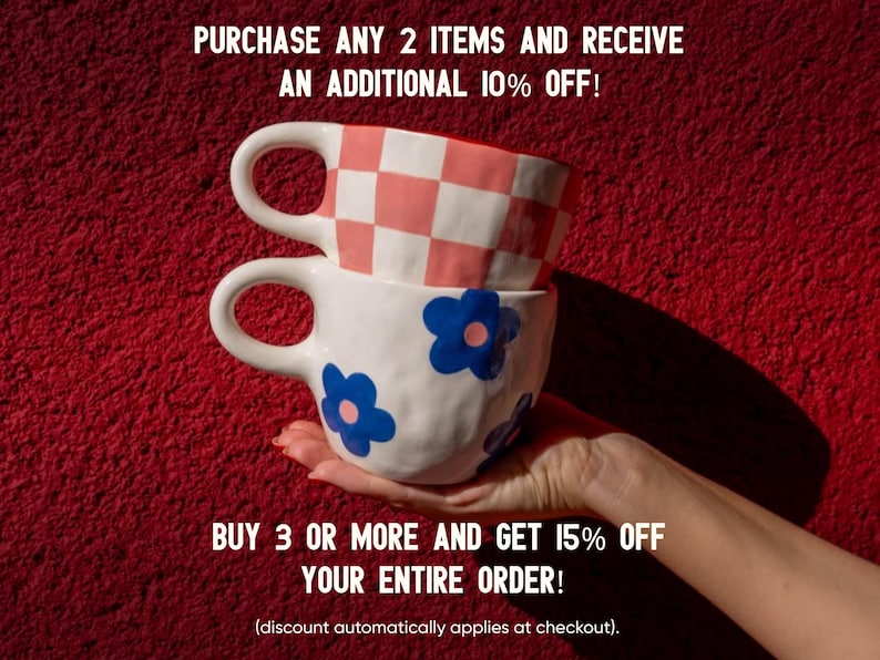 May include: Two ceramic mugs stacked on top of each other, held by a hand, against a red background. The top mug has a pink and white checkered pattern, while the bottom mug is white with blue flower designs. Text on the image reads: "PURCHASE ANY 2 ITEMS AND RECEIVE AN ADDITIONAL 10% OFF! BUY 3 OR MORE AND GET 15% OFF YOUR ENTIRE ORDER!"