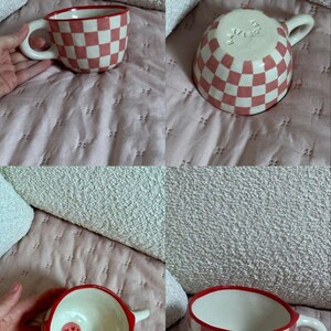 May include: A ceramic mug with a red and white checkered pattern. The rim and handle are red. The interior is white with a small smiley face. The mug is on a pink quilted surface.