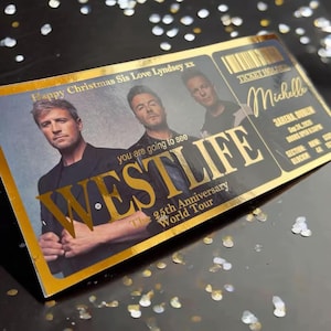 May include: A gold and black ticket for the Westlife 25th Anniversary World Tour. The ticket features a photo of the band members and the text "WESTLIFE" in gold lettering. The ticket also includes the venue, date, and the name "Michelle".