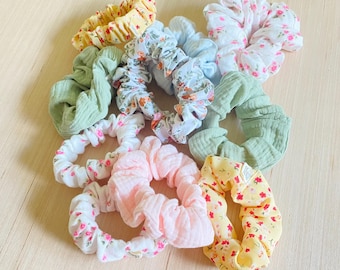 May include: A collection of 10 colorful hair scrunchies with floral patterns. The scrunchies are made of soft fabric and are perfect for adding a touch of style to any outfit.