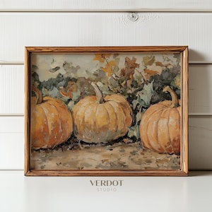 Könnte beinhalten: Ein gerahmtes Gemälde mit drei Kürbissen in einer herbstlichen Umgebung. Die Kürbisse sind hellorange und von grünen Blättern umgeben. Das Gemälde ist vor einem weißen Hintergrund platziert.