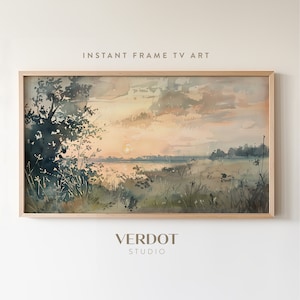 May include: Watercolor landscape art print in a light wood frame. The artwork depicts a sunset over a body of water, with grassy fields and trees in the foreground. The text "INSTANT FRAME TV ART" and "VERDOT STUDIO" are visible.