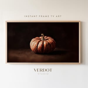 以下が含まれることがあります： オレンジと茶色のカボチャのデジタルアートプリント。暗い背景に設定され、「INSTANT FRAME TV ART」と「VERDOT STUDIO」のテキストが含まれています。明るい木製のフレームに入っています。
