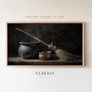 May include: A framed print featuring a still life with a cauldron, small bowl, and broom. The print has a dark, moody aesthetic. The text "INSTANT FRAME TV ART" is at the top, and "VERDOT STUDIO" is at the bottom.