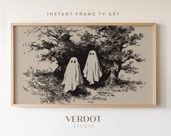 May include: Framed artwork featuring two ghost figures in a forest setting. The artwork is a black and white illustration with the text "INSTANT FRAME TV ART" at the top and "VERDOT STUDIO" at the bottom. The frame is a light wood color.