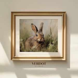 May include: A framed painting of a brown rabbit sitting in a field of green grass. The rabbit is looking directly at the viewer. The frame is gold and has a white mount.