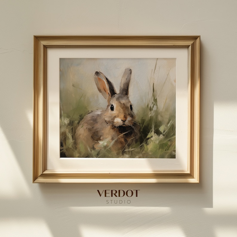 May include: A framed painting of a brown rabbit sitting in a field of green grass. The rabbit is looking directly at the viewer. The frame is gold and has a white mount.