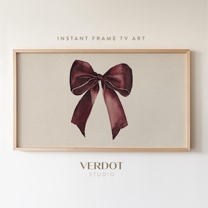 May include: A watercolor painting of a burgundy bow on a beige background, framed in a light wood. The text "INSTANT FRAME TV ART" is at the top, and "VERDOT STUDIO" is at the bottom.
