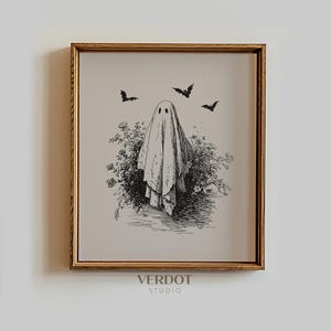 May include: A framed black and white illustration of a ghost figure with three bats flying above a bush. The artwork is in a gold frame and is a vintage style print. The text "VERDOT STUDIO" is at the bottom.