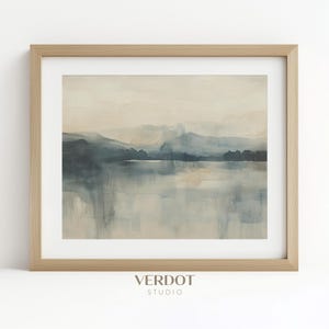 May include: A framed watercolor painting of a misty lake scene with a mountain range in the background. The painting is in shades of blue and gray, with a light brown frame.