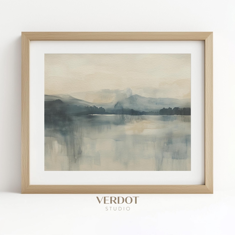 May include: A framed watercolor painting of a misty lake scene with a mountain range in the background. The painting is in shades of blue and gray, with a light brown frame.