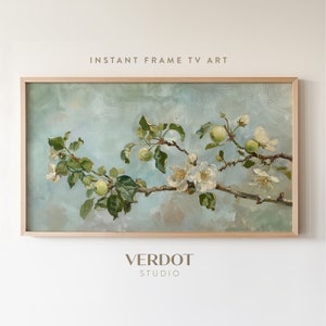 May include: A framed painting of a branch of a flowering apple tree with white blossoms and green apples against a light blue background. The painting is in a light wood frame. The text "INSTANT FRAME TV ART" is above the painting and the text "VERDOT STUDIO" is below the painting.