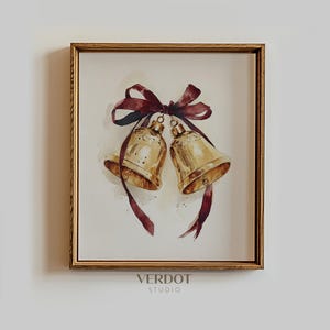 Pode incluir: Pintura em aquarela de dois sinos dourados amarrados com uma fita bordô. Os sinos estão em uma moldura de madeira. A pintura tem uma paleta de cores suaves e quentes e é assinada "VERDOT STUDIO".