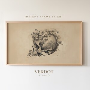 May include: A black and white illustration of a human skull with a crown of white flowers on top. The image is framed in a light wood frame.