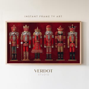 May include: A framed print featuring six detailed nutcracker figures in red and gold uniforms, set against a deep red background. The print includes the text "INSTANT FRAME TV ART" and the "VERDOT STUDIO" logo.