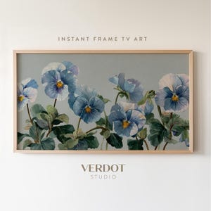 May include: A framed print of blue pansies with yellow centres and green leaves on a muted grey backdrop. The text "INSTANT FRAME TV ART" is at the top, and "VERDOT STUDIO" is at the bottom.