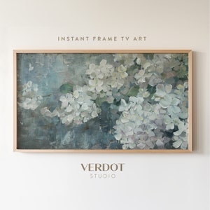 May include: A framed painting of white flowers with a blue and green background. The painting is in a light wood frame. The text "INSTANT FRAME TV ART" is above the painting and the text "VERDOT STUDIO" is below the painting.