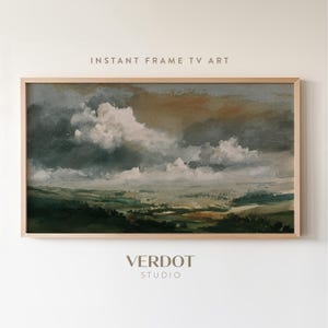 May include: A framed landscape painting with a cloudy sky and green fields. The artwork is in a wooden frame and features the text "INSTANT FRAME TV ART" at the top and "VERDOT STUDIO" at the bottom.