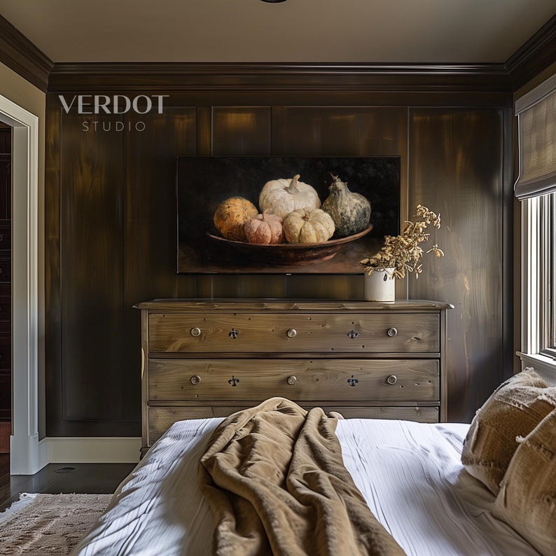 May include: A bedroom scene featuring a wooden dresser with three drawers, topped with a painting of pumpkins in a bowl. The wall behind the dresser is dark wood paneling. A bed with a white comforter and brown blanket is in the foreground. The text "VERDOT STUDIO" is visible.