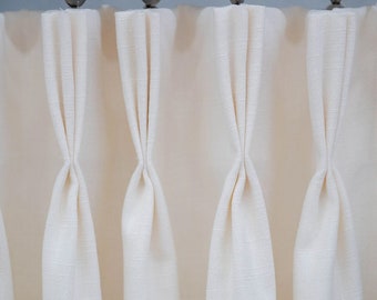 May include: Close-up of white curtains with pleats hanging from a metal curtain rod.