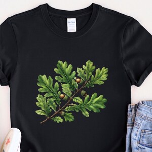 May include: Black t-shirt with a green oak leaf and acorn illustration.