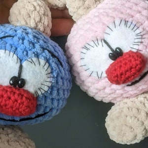 May include: Two crocheted plush toys with big eyes and red noses. One is blue and the other is pink.